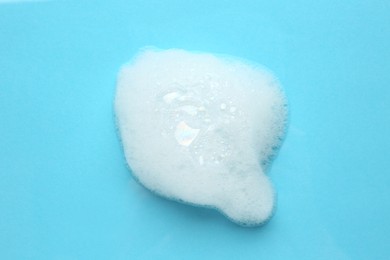 Photo of Drop of bath foam on turquoise background, top view