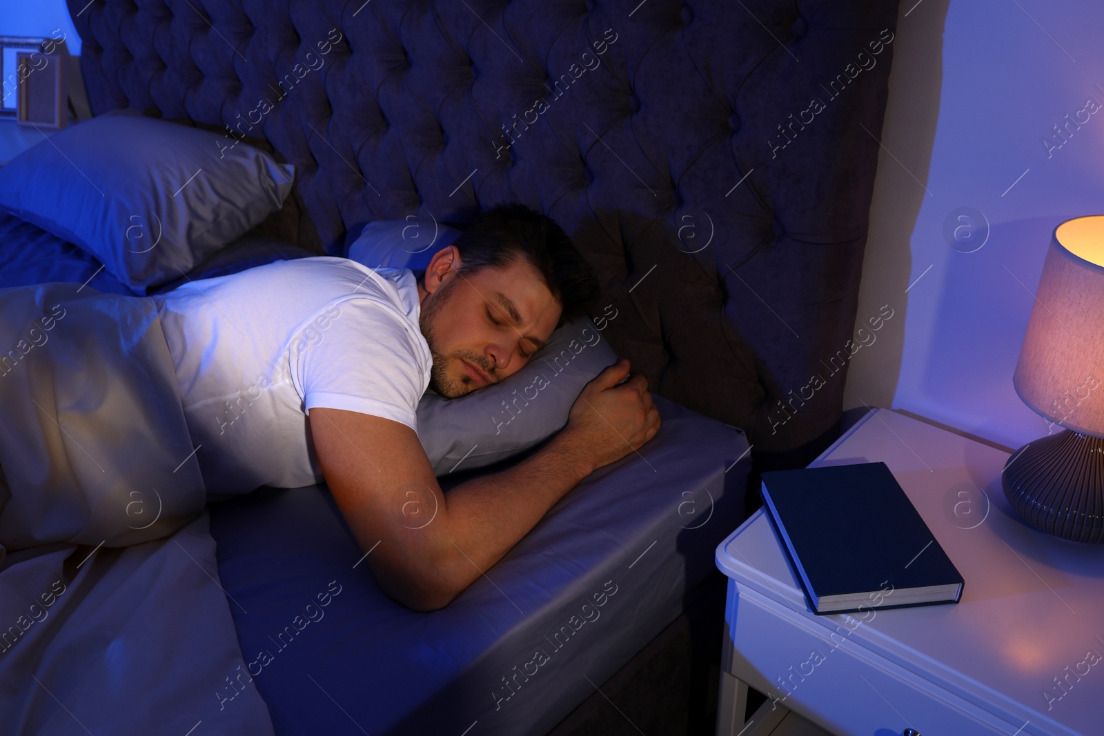 Photo of Handsome man sleeping on pillow in dark room at night. Bedtime