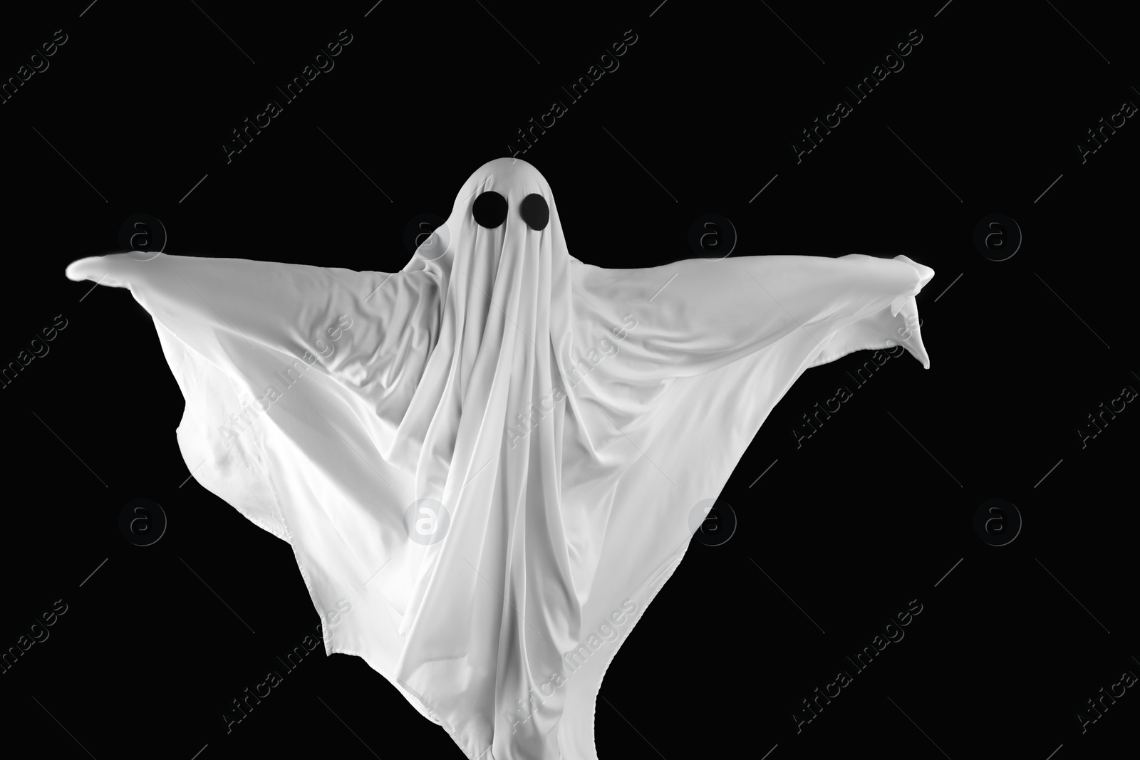 Photo of Creepy ghost. Person covered with white sheet on black background