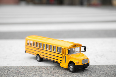 Yellow toy school bus on road outdoors. Transport for students