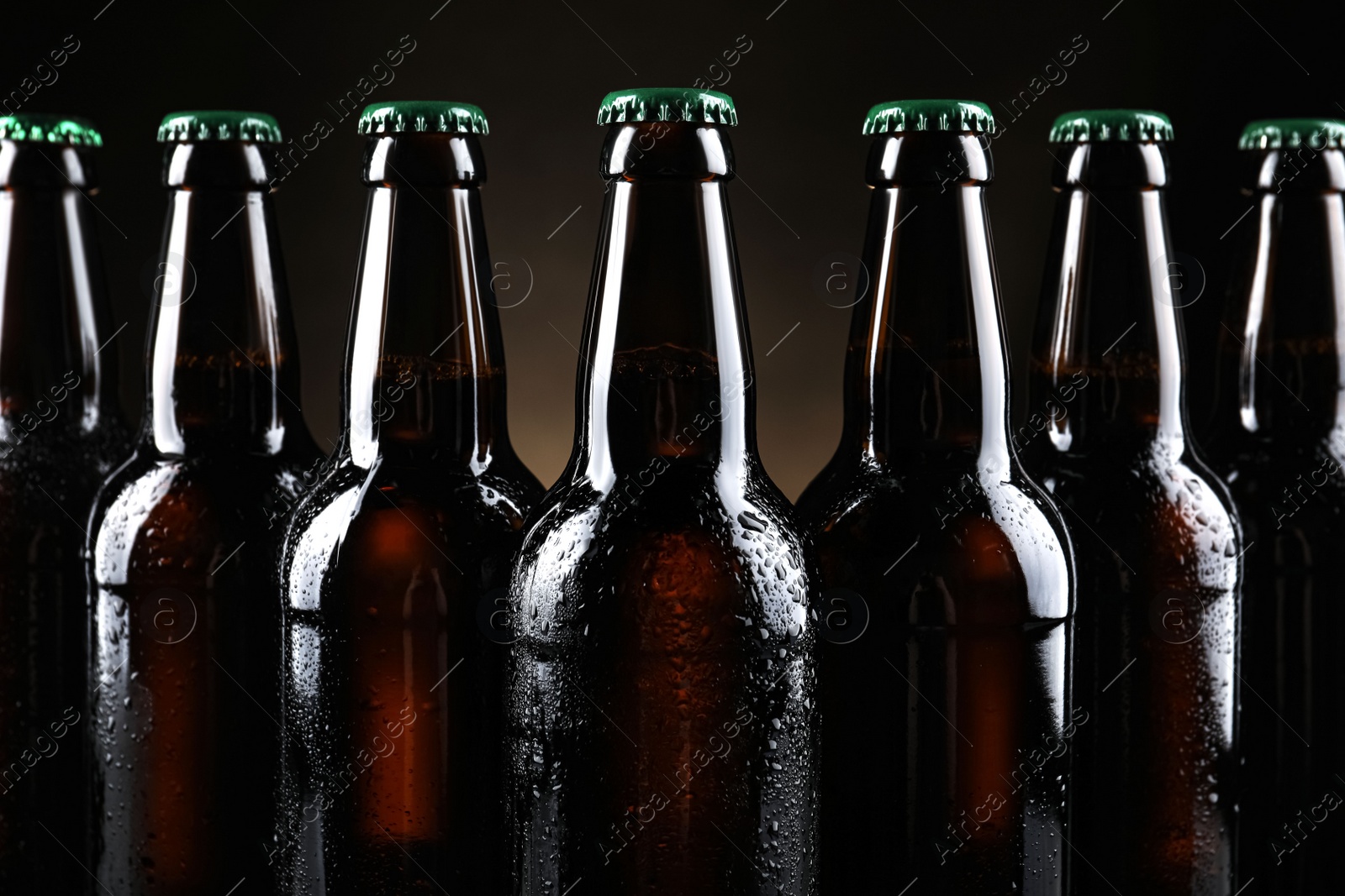 Photo of Many bottles of beer on dark background, closeup