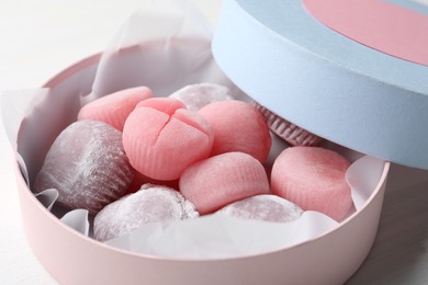 Many different delicious mochi in box on white wooden table, closeup. Traditional Japanese dessert