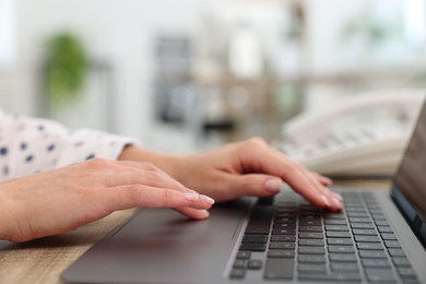 Secretary working with laptop at table in office, closeup