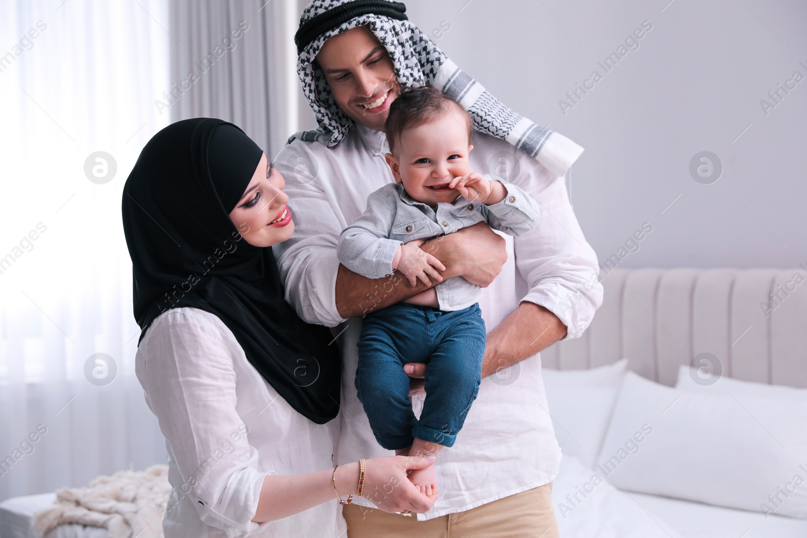 Photo of Happy Muslim family with little son in bedroom