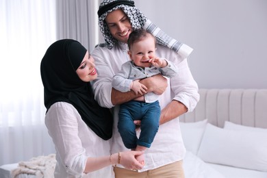 Happy Muslim family with little son in bedroom