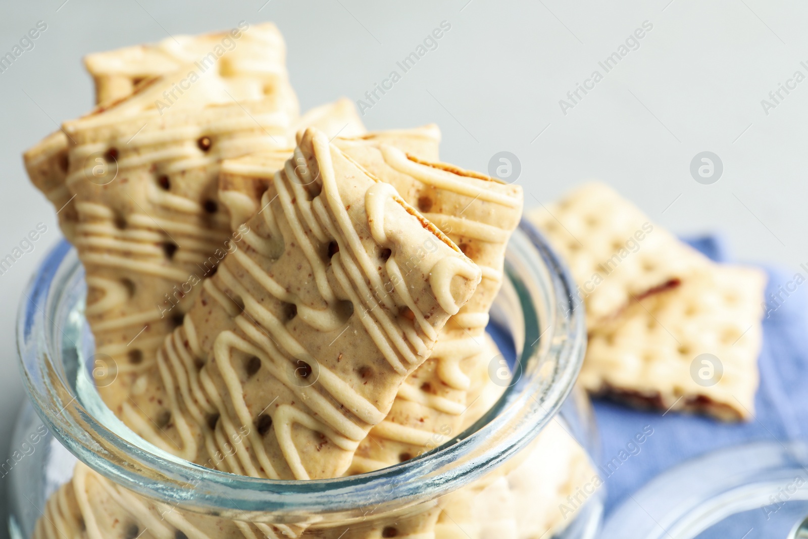 Photo of Tasty cookies with icing in glass jar on table, closeup