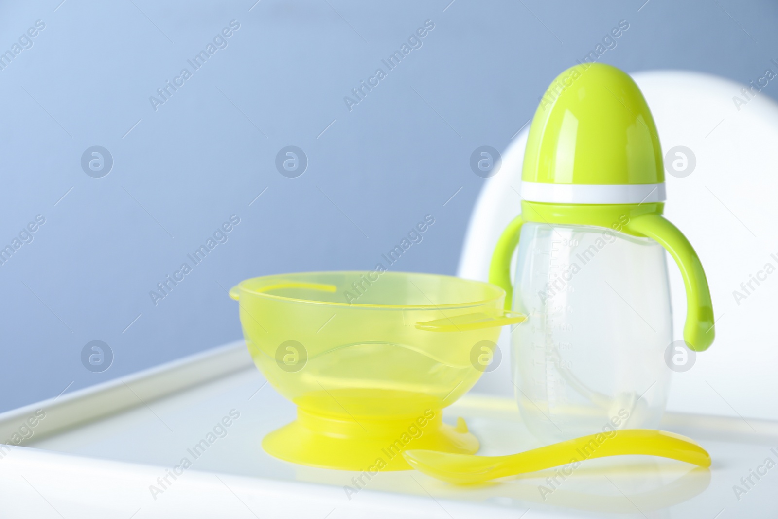 Photo of Set of plastic dishware on white feeding table. Serving baby food