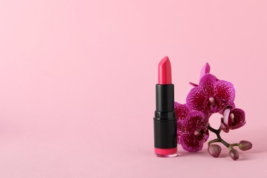 Beautiful lipstick and orchid flowers on pink background, space for text