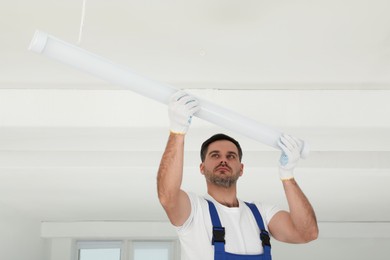Photo of Electrician installing led linear lamp indoors. Ceiling light