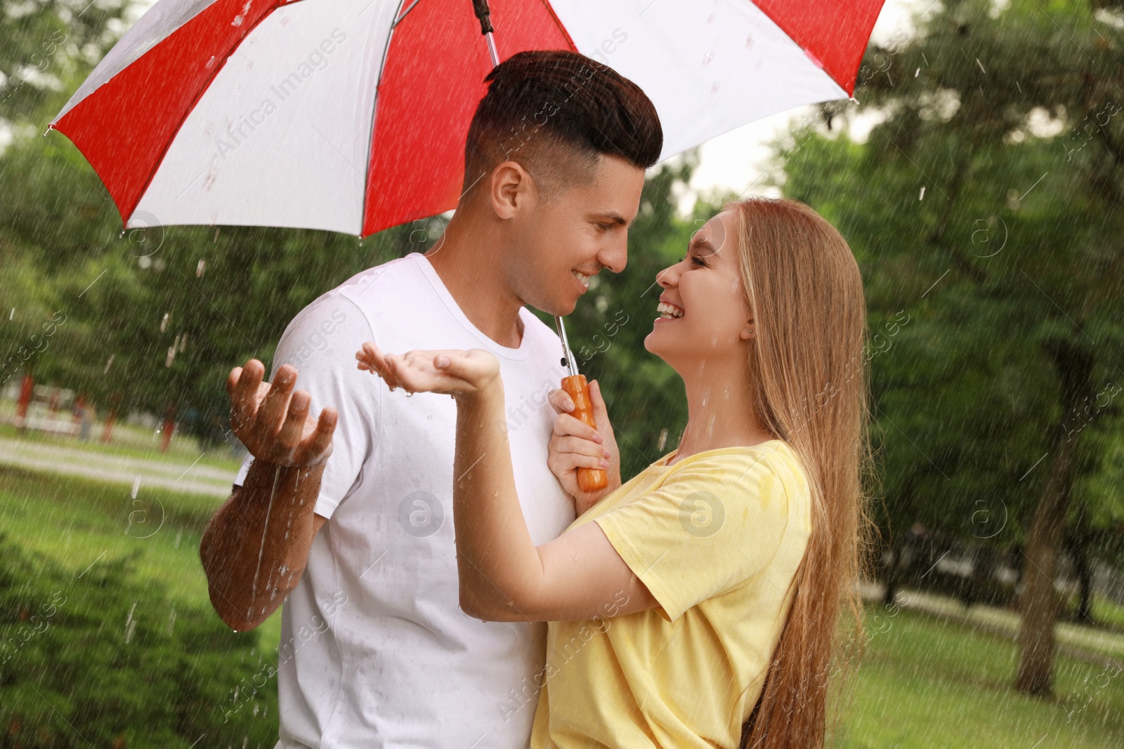 Photo of Lovely couple with umbrella walking under rain in park