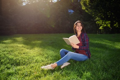 Photo of Young woman with book in park on sunny day