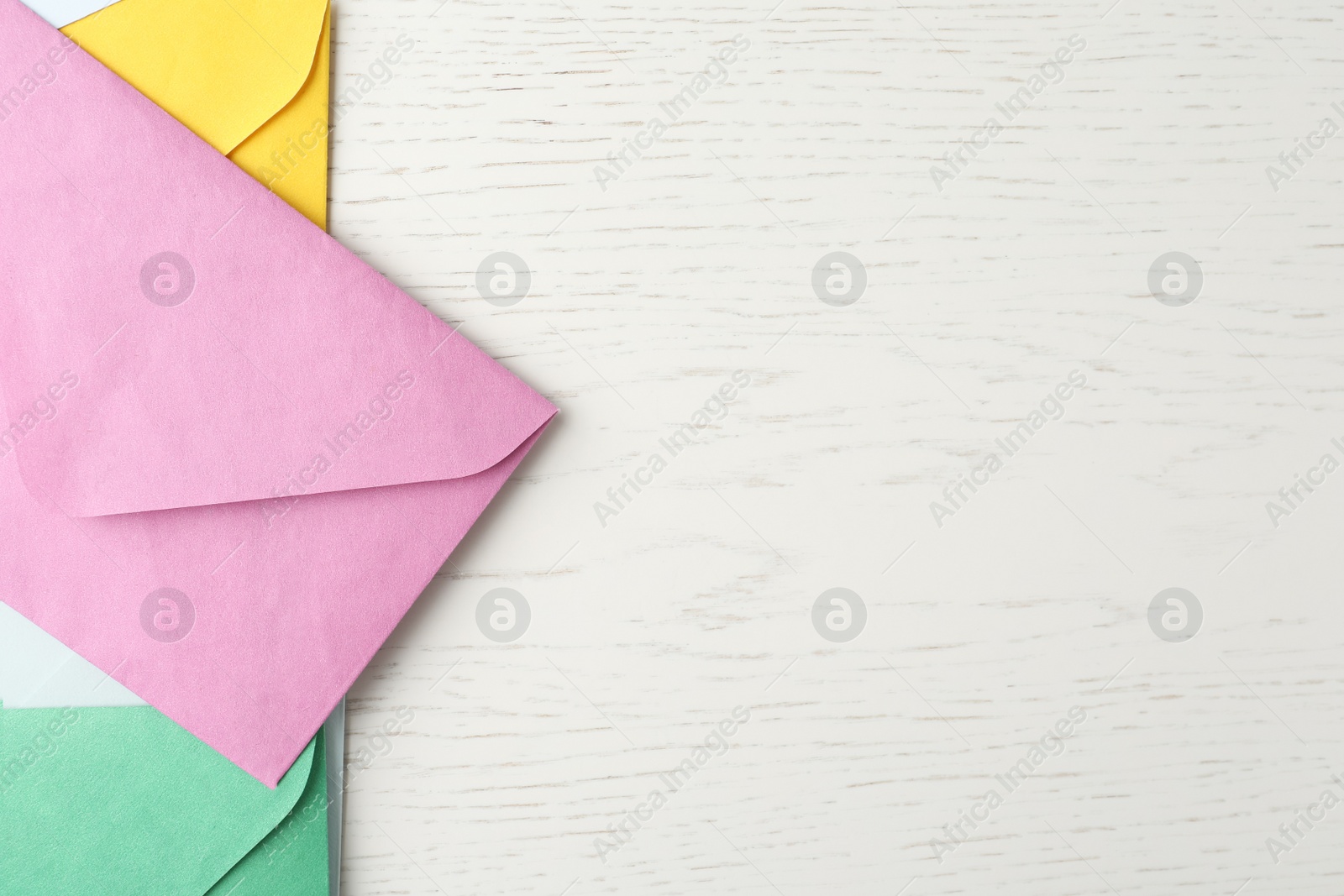 Photo of Colorful paper envelopes on white wooden background, flat lay. Space for text