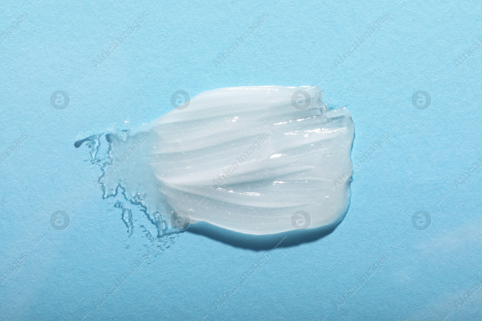 Photo of Smear of ointment on light blue background, top view