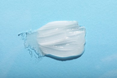 Smear of ointment on light blue background, top view