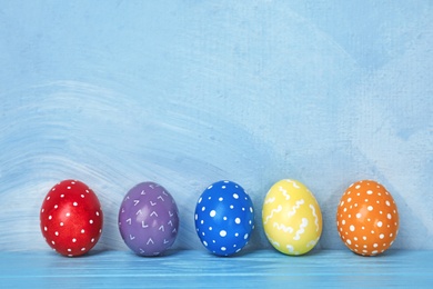 Photo of Decorated Easter eggs on table near color wall. Space for text