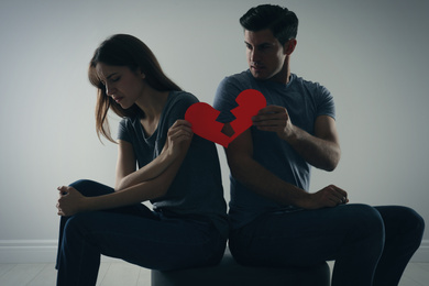 Photo of Couple with torn paper heart on grey background. Relationship problems