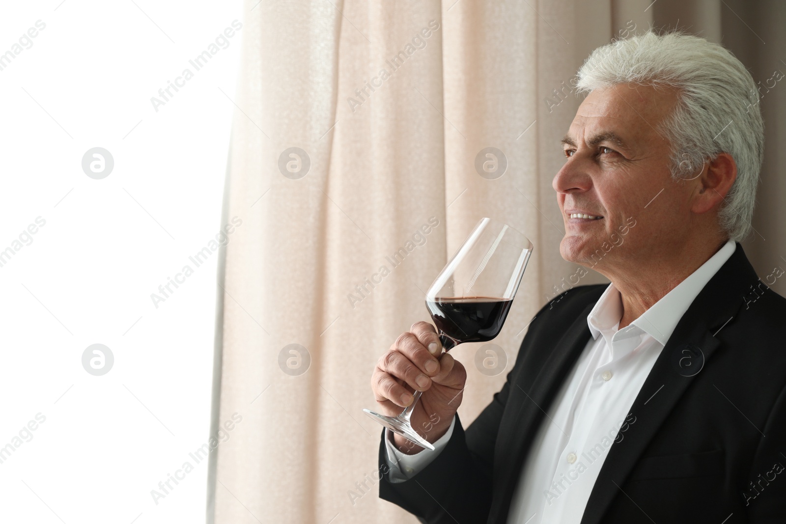 Photo of Senior man with glass of wine indoors. Space for text