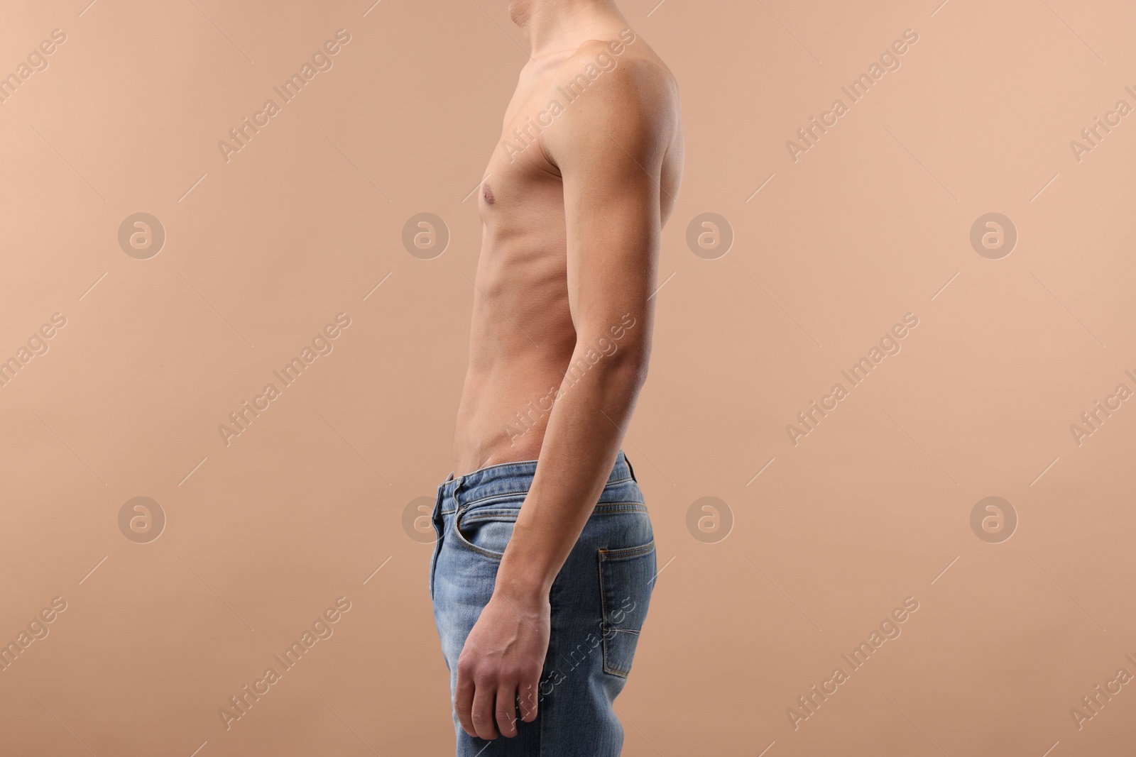 Photo of Shirtless man with slim body on beige background, closeup