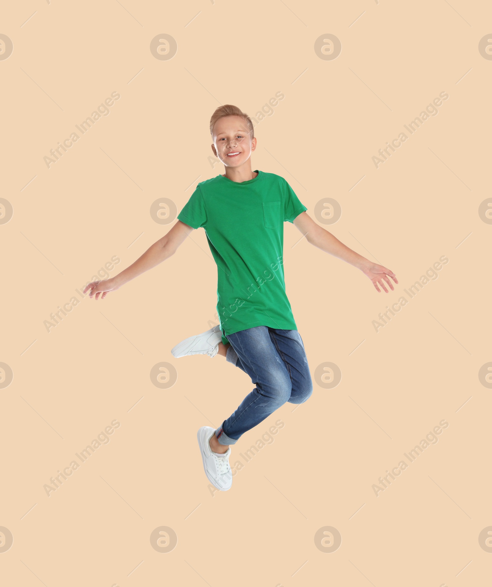 Image of Teenage boy jumping on beige background, full length portrait