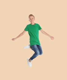 Image of Teenage boy jumping on beige background, full length portrait