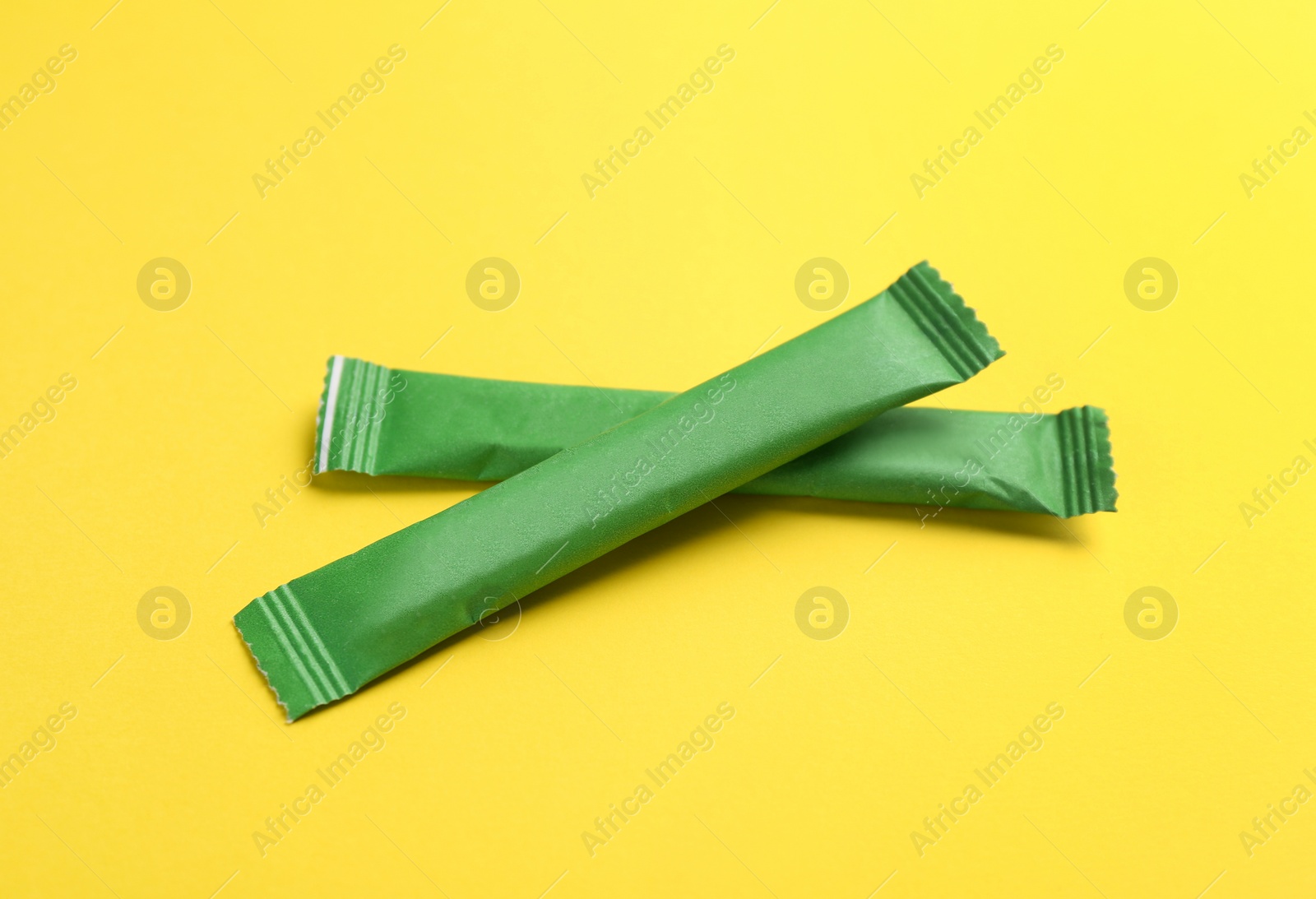 Photo of Green sticks of sugar on yellow background