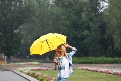 Photo of Happy young woman with umbrella under rain in park