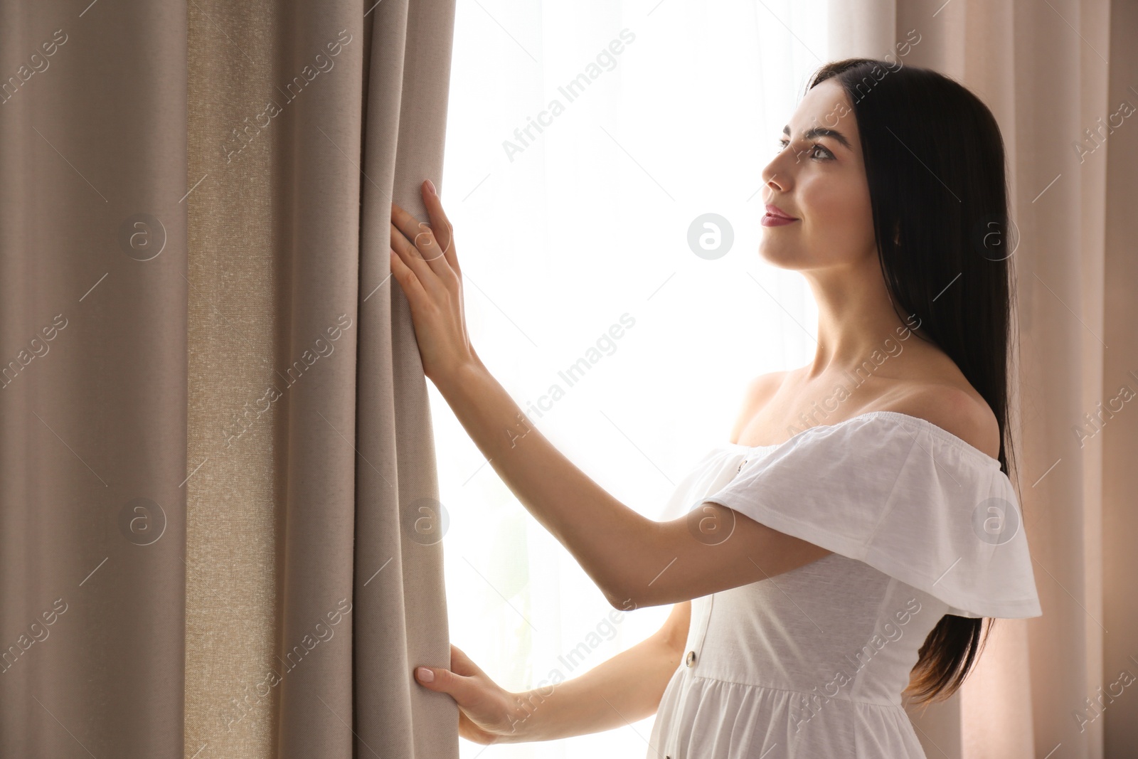 Photo of Woman opening window curtain at home in morning