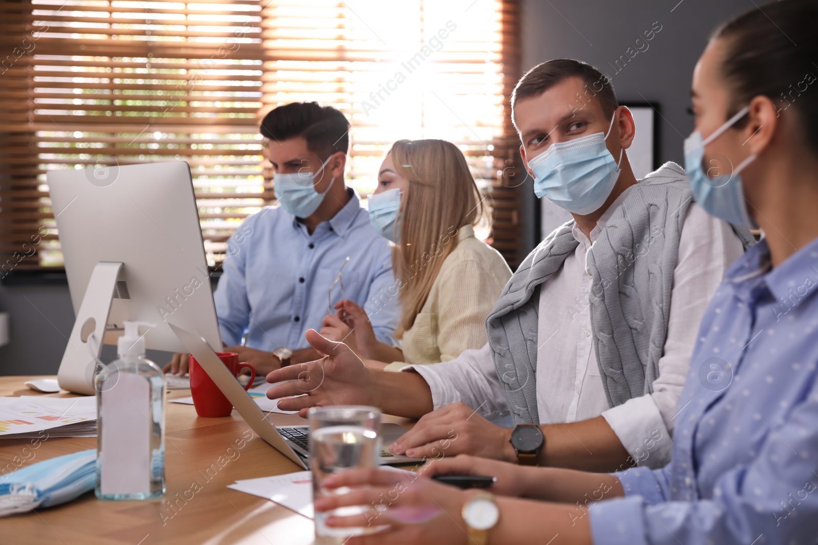 Photo of Coworkers with masks in office. Protective measure during COVID-19 pandemic