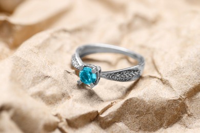 Photo of Beautiful ring with light blue gemstone on kraft paper. Luxury jewelry