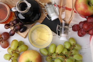 Photo of Different types of vinegar and fresh fruits on white table, flat lay