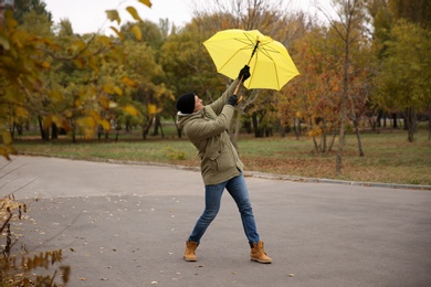 Photo of Man with yellow umbrella caught in gust of wind outdoors