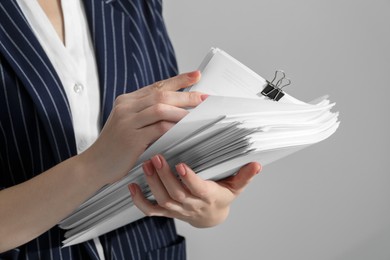 Photo of Woman stacking documents on grey background, closeup