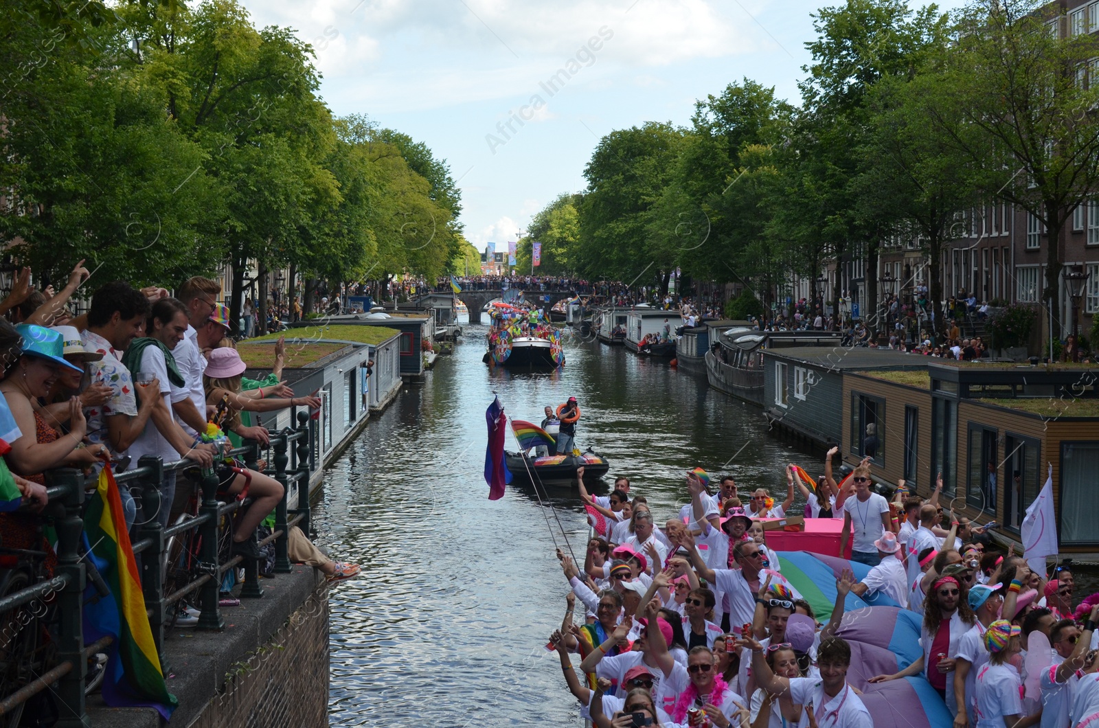 Photo of AMSTERDAM, NETHERLANDS - AUGUST 06, 2022: Many people in boats at LGBT pride parade on river