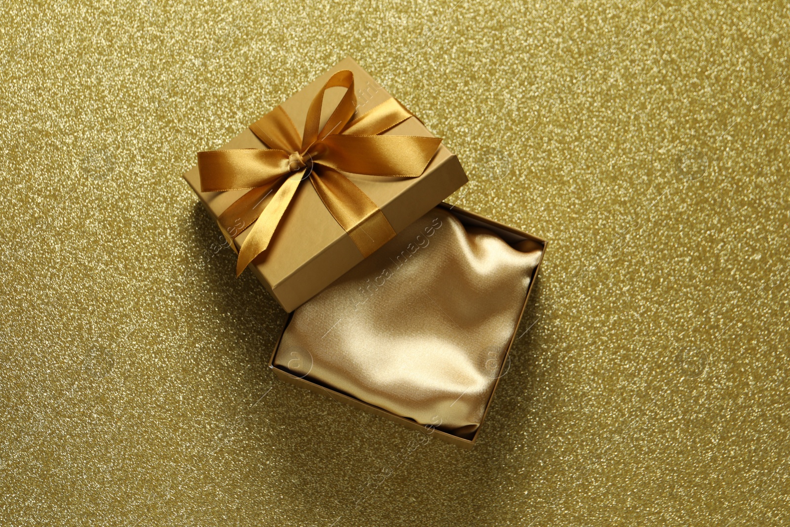 Photo of Open gift box on golden background, top view