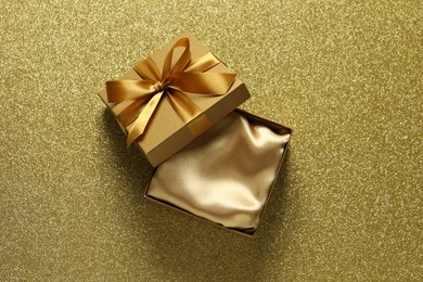 Photo of Open gift box on golden background, top view