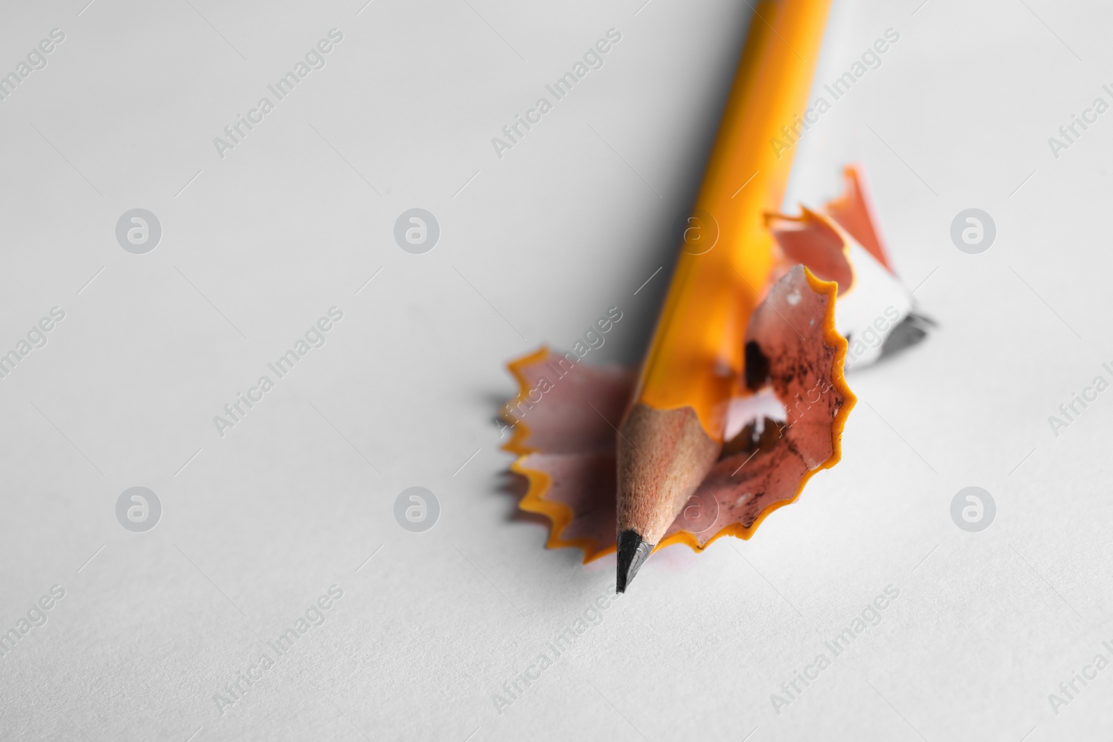 Photo of One sharp graphite pencil and shavings on white background, closeup. Space for text