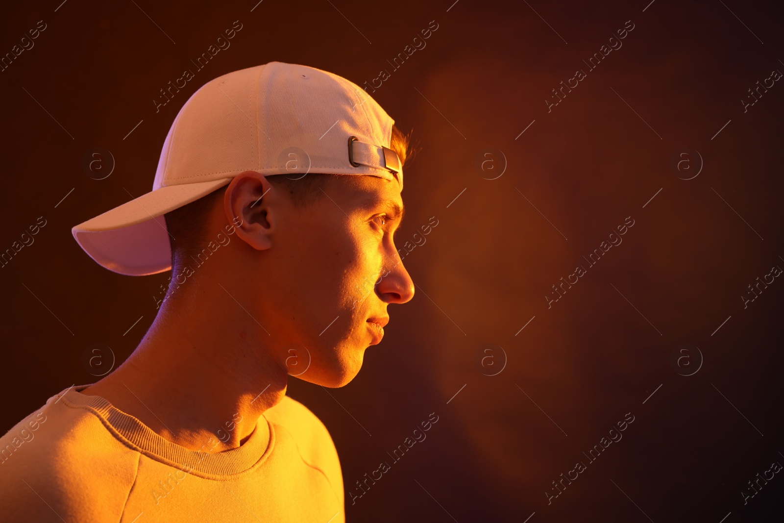 Photo of Young man on brown background in neon light. Space for text