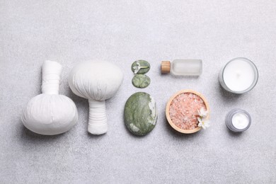 Flat lay composition with herbal massage bags and spa products on light grey table