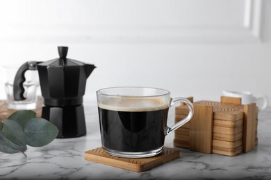 Photo of Mug of hot drink and stylish cup coasters in holder on marble table