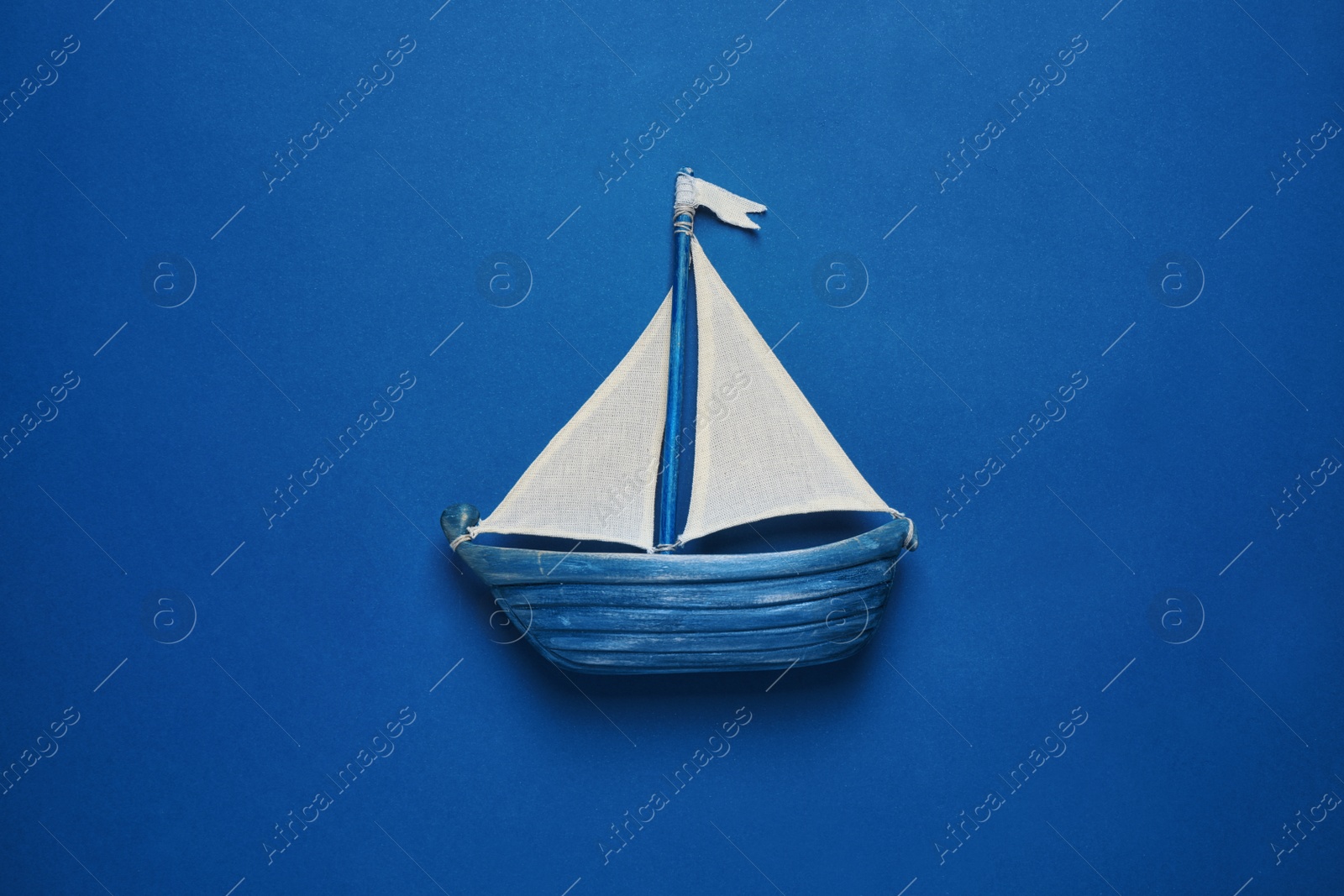 Photo of Toy ship on bright background, top view. Color of the year 2020 (Classic blue)