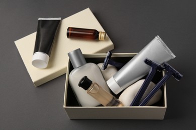 Different men's shaving accessories and box on dark grey background