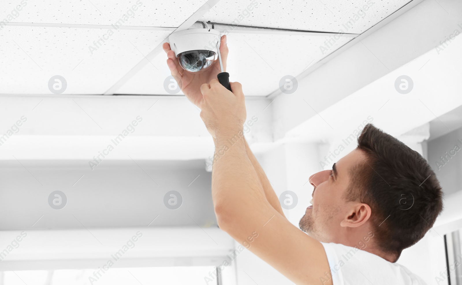 Photo of Technician installing CCTV camera on ceiling indoors