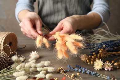 Photo of Florist making bouquetdried flowers at wooden table, closeup