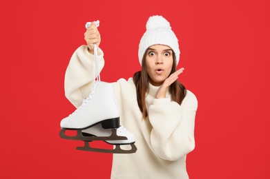 Emotional woman with ice skates on red background