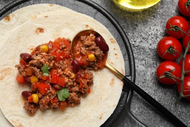 Photo of Tasty chili con carne with tortilla and tomatoes on grey table, flat lay