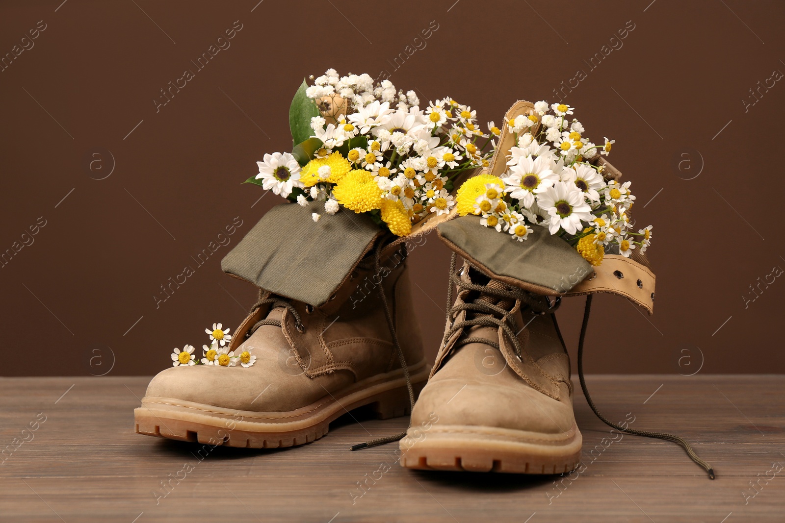 Photo of Boots with beautiful flowers on wooden surface