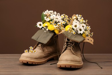 Boots with beautiful flowers on wooden surface