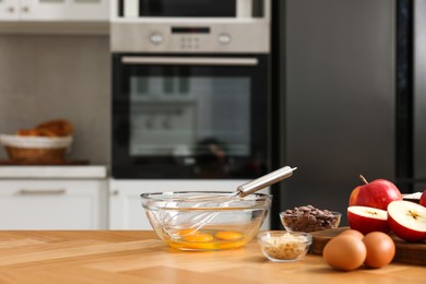 Cooking process. Metal whisk, bowl and products on wooden table in kitchen. Space for text