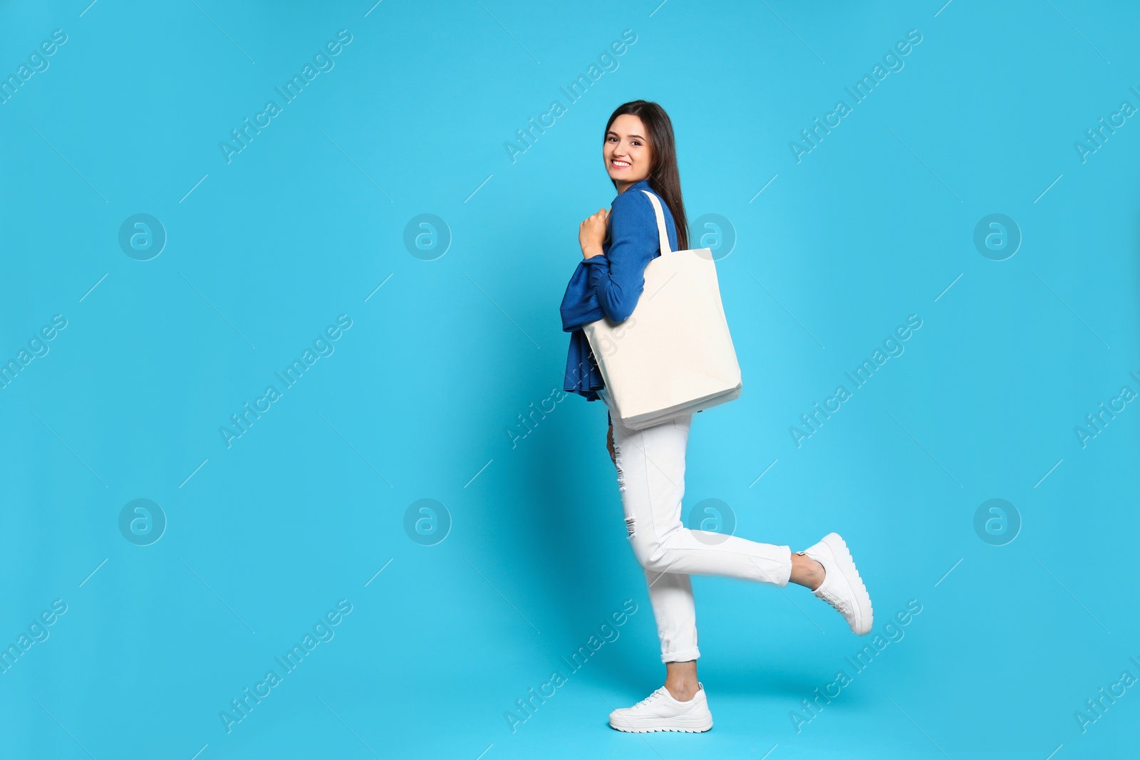 Photo of Beautiful young woman with stylish blank eco bag against color background, space for text