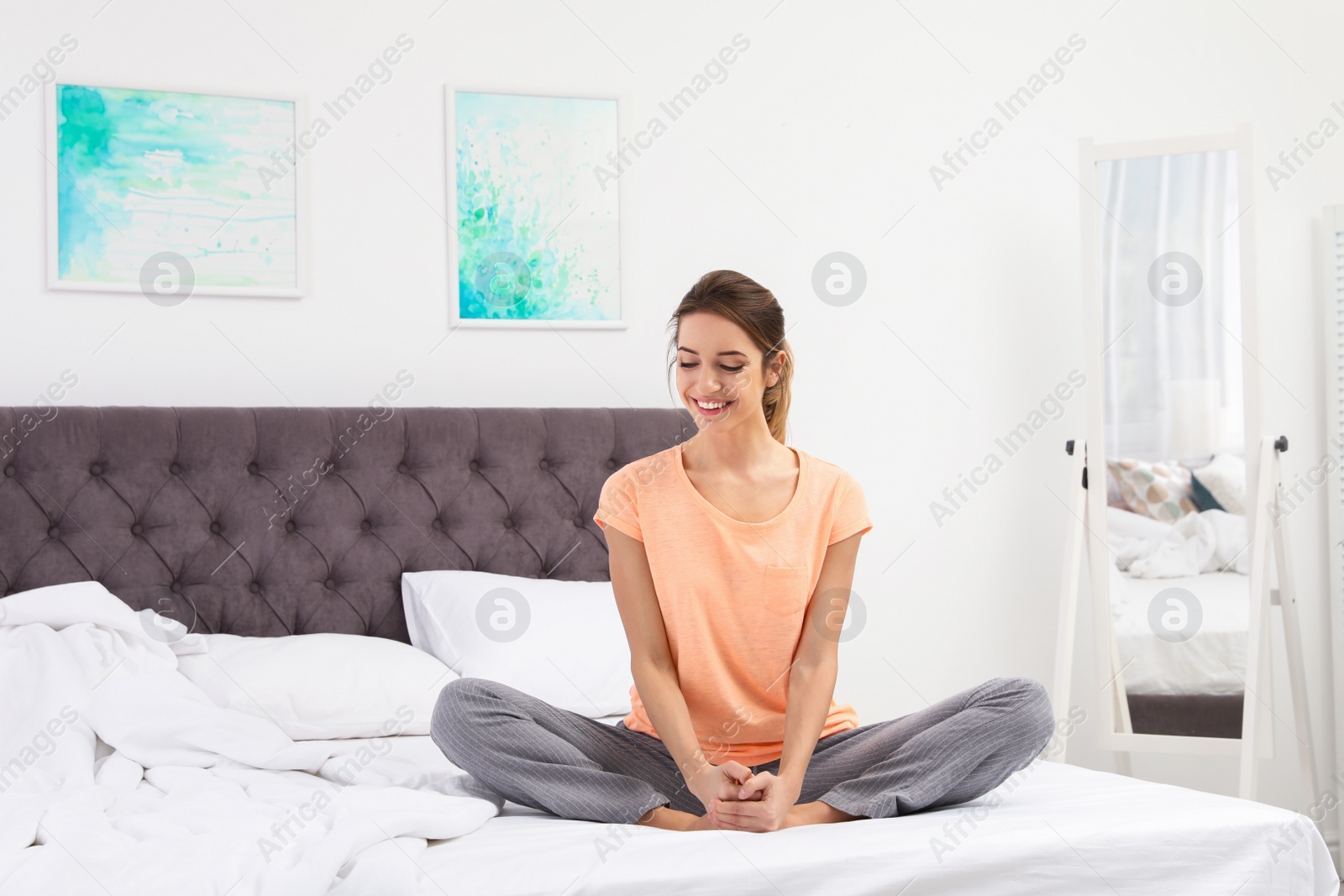 Photo of Young beautiful woman doing exercise on bed at home. Morning fitness